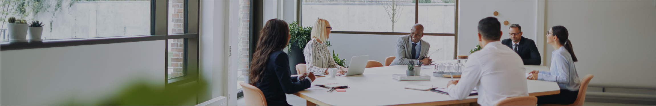 Smiling group of diverse businesspeople sitting around a boardroom table in an office during a meeting