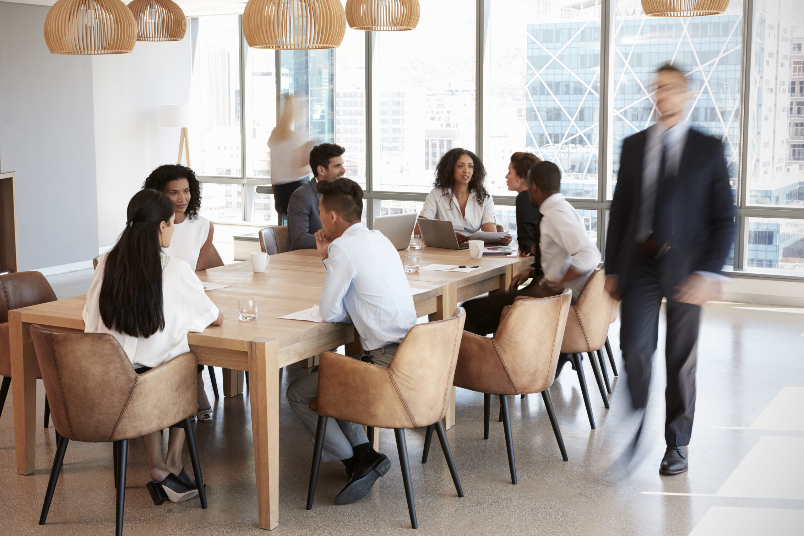 Group Of Businesspeople Sitting Around Table In Meeting Room