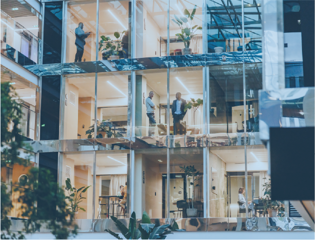 Glass office building with business people working in offices.