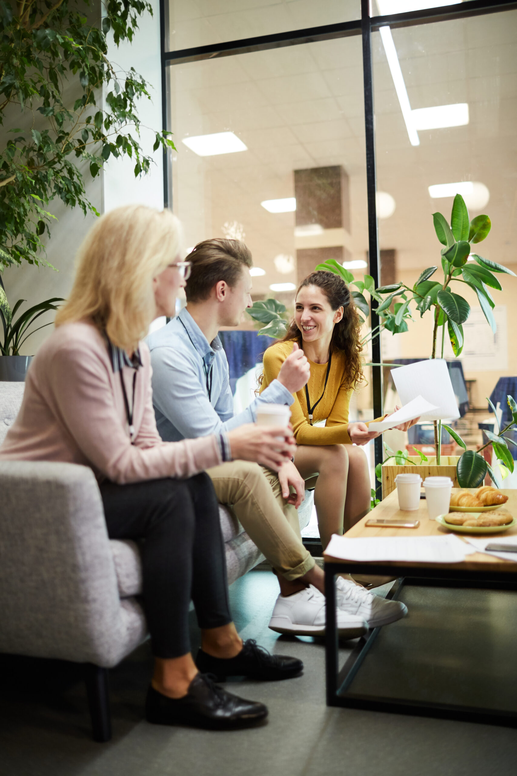 Group of casual managers sitting on sofa while discussing working questions and new ideas at start-up meeting