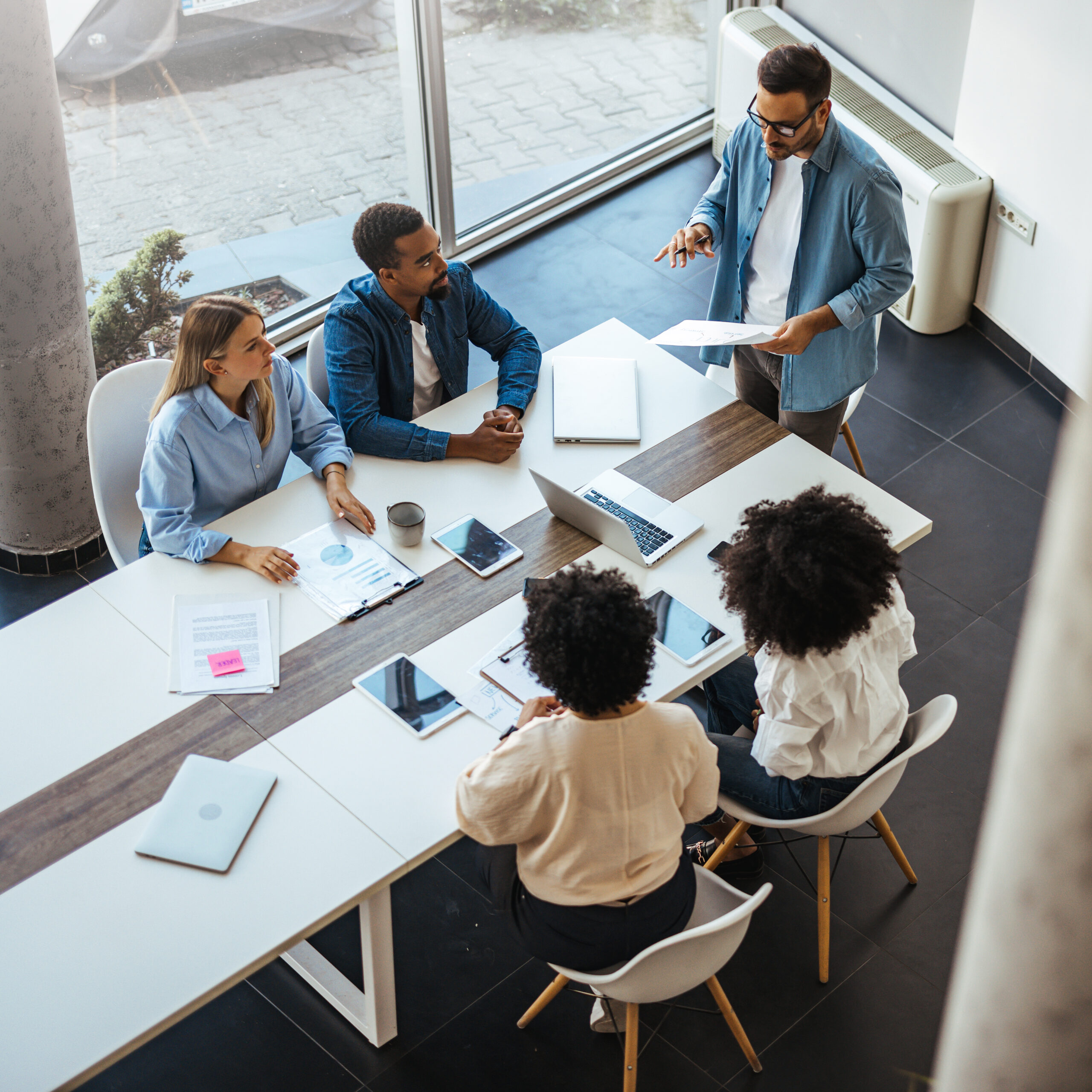 A diverse group of professionals in a modern office setting engaged in a collaborative business meeting.